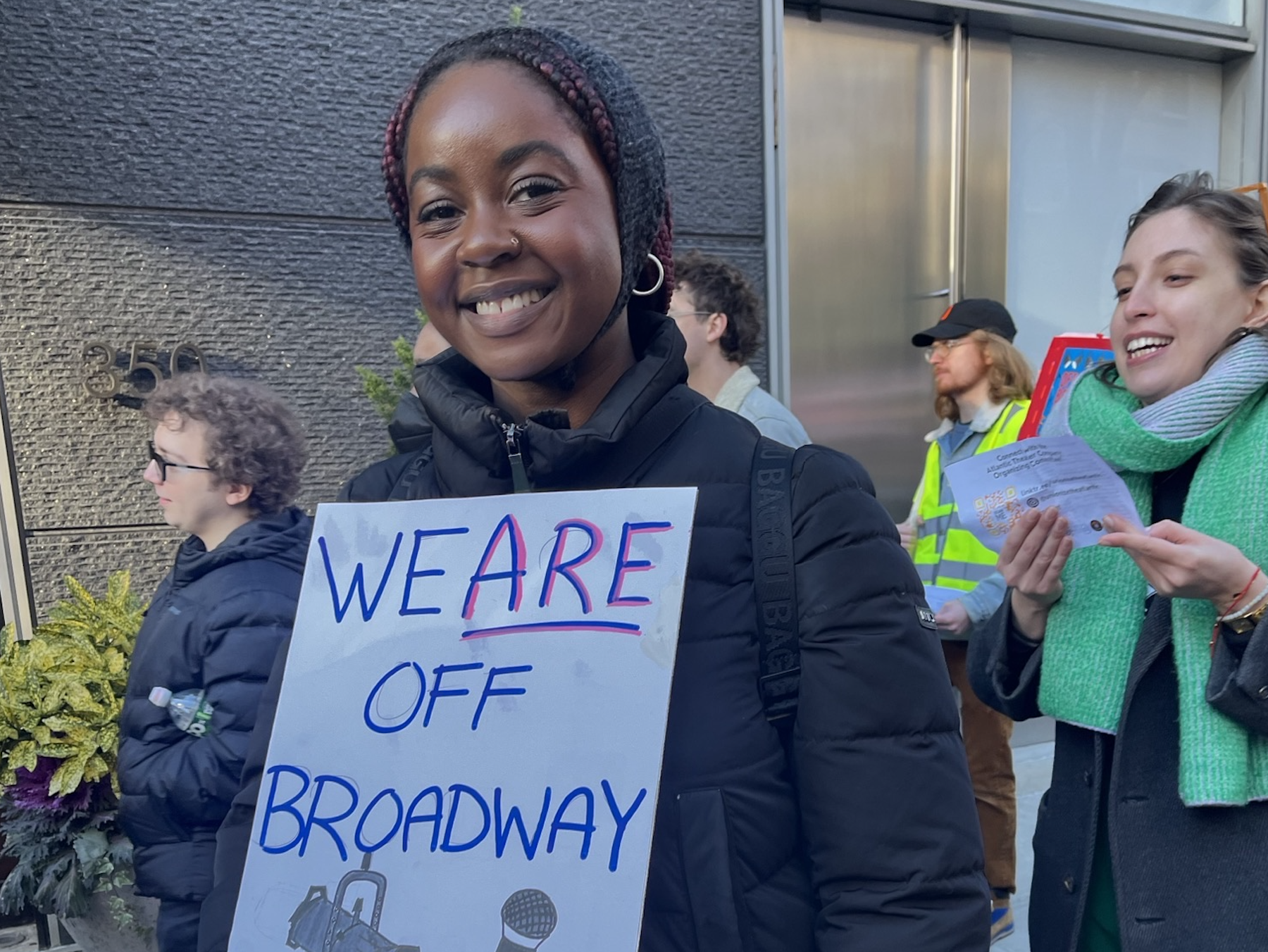 An IATSE member at a protest holding a sign that reads "We Are Off Broadway"